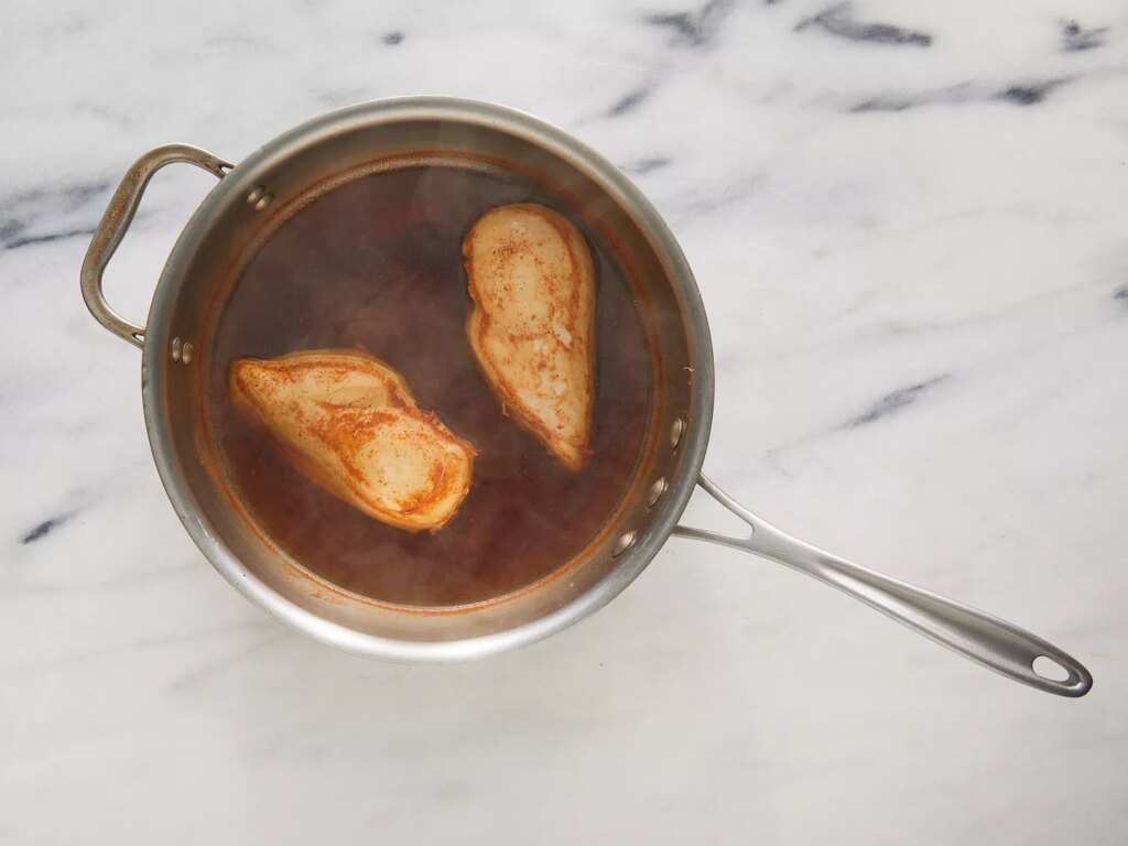 Overhead of chicken cooking in a pot full of water and spices.