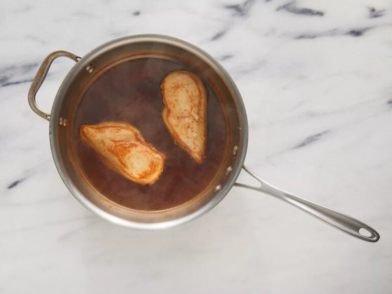 Overhead of chicken cooking in a pot full of water and spices.