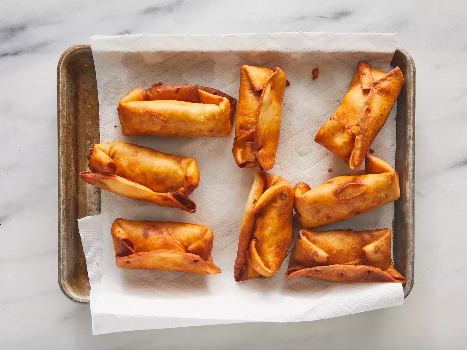 Overhead of cooked chimichangas drying on a paper towel. 
