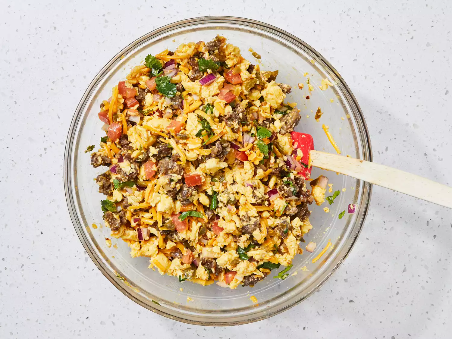 Sausage combined with the rest of the ingredients in a large bowl.