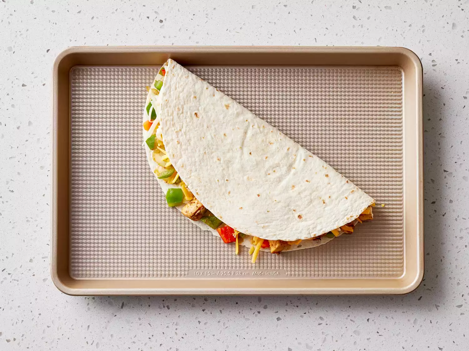 tortilla folded over and placed on a baking sheet