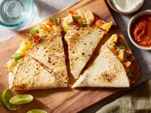Looking down at a chicken quesadilla cut into fours, and served with sauces