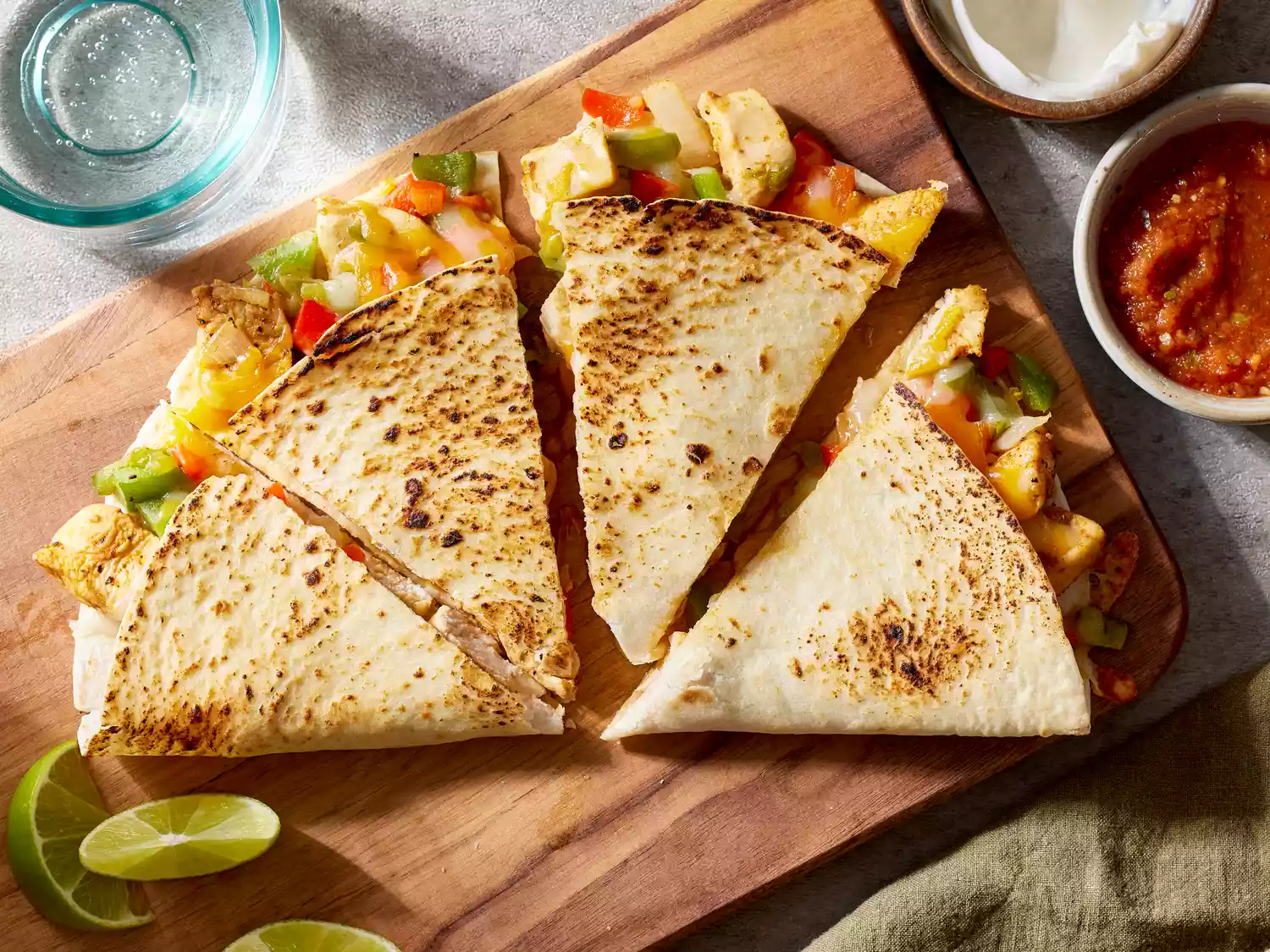 Looking down at a chicken quesadilla cut into fours, and served with sauces