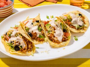 A plate of tacos garnished with various toppings and sauce