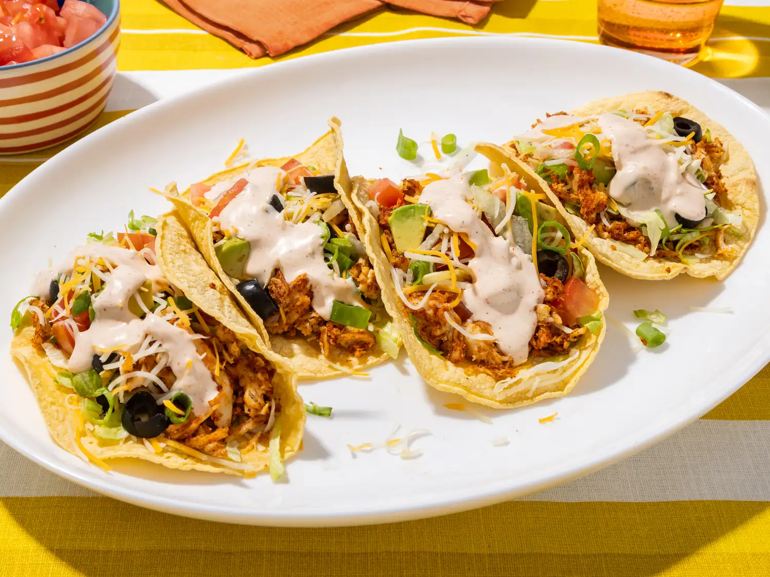 A plate of tacos garnished with various toppings and sauce