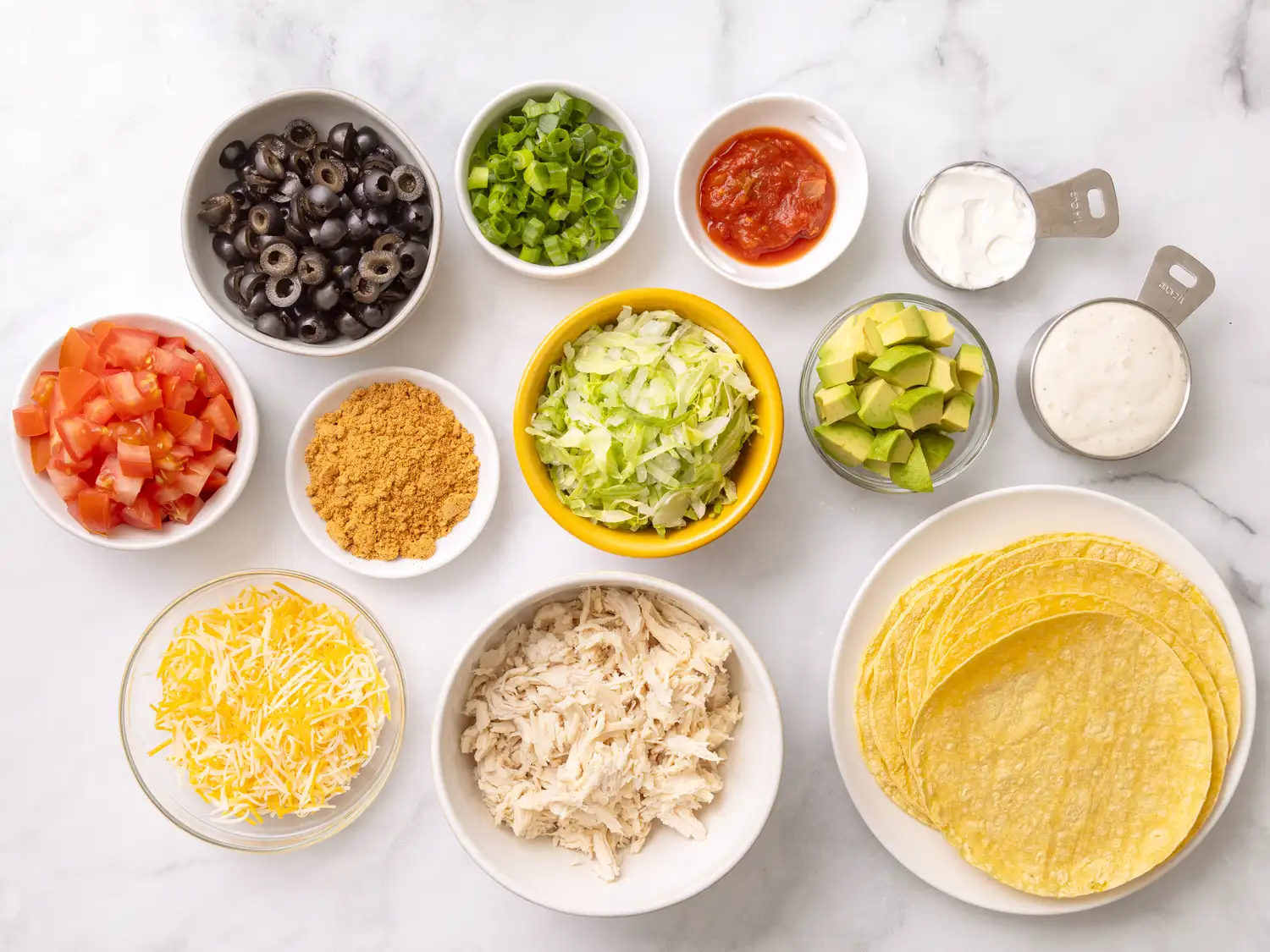 Prepared ingredients for making tacos organized in different bowls and plates on a countertop