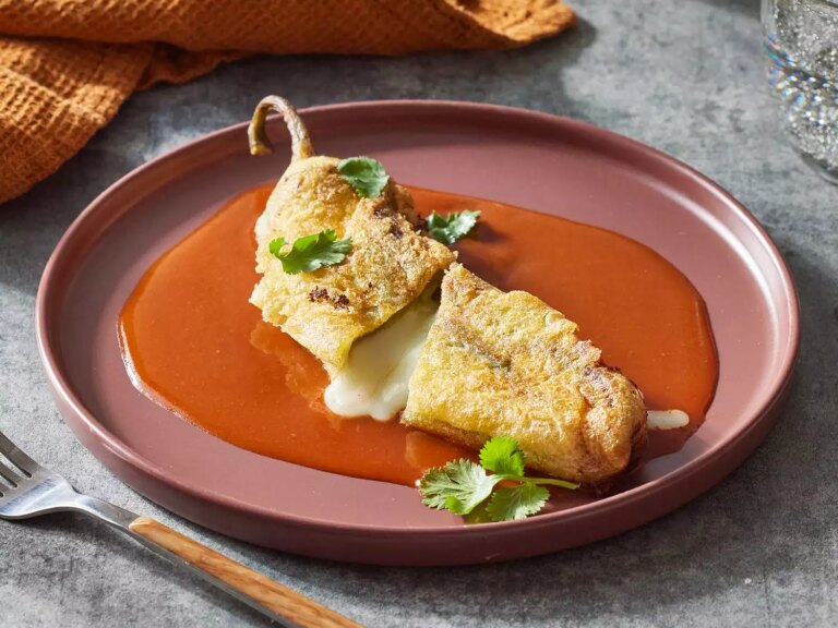 Close up on a single chile rellenos cut in half, and served on a plate