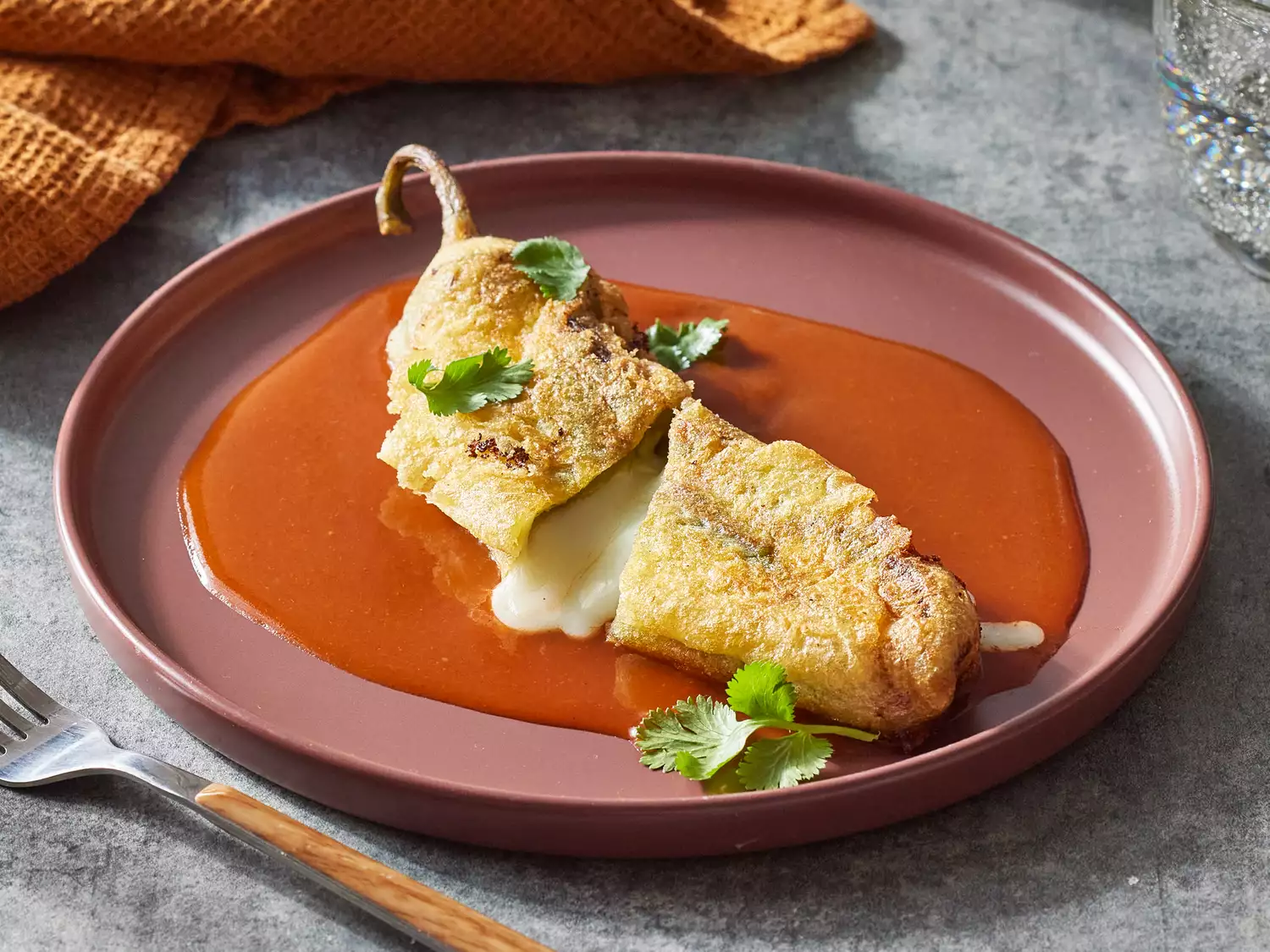 Close up on a single chile rellenos cut in half, and served on a plate