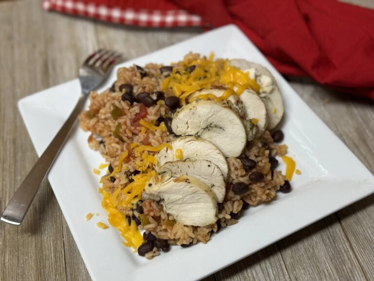 Sliced chicken breast sitting on top of mexican rice and cheese