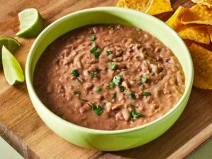 A large bowl of refried beans, garnished with chopped cilantro