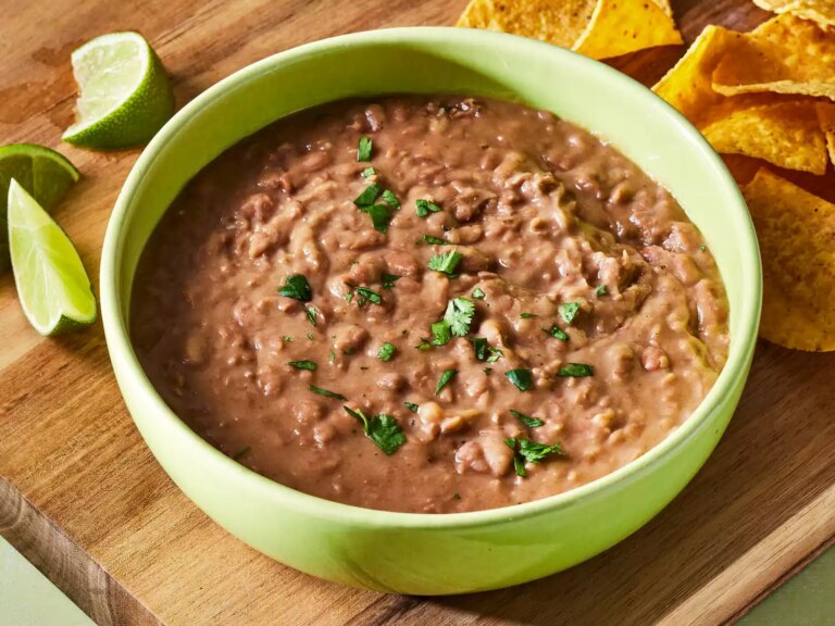 A large bowl of refried beans, garnished with chopped cilantro