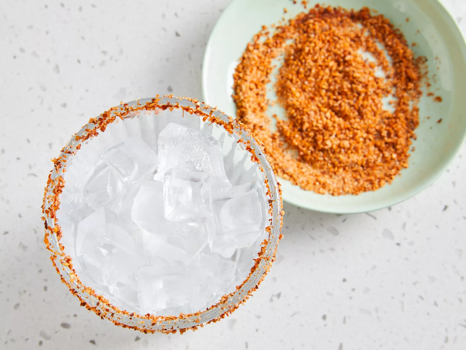 an overhead shot of ice in a glass and chili season covering the rim