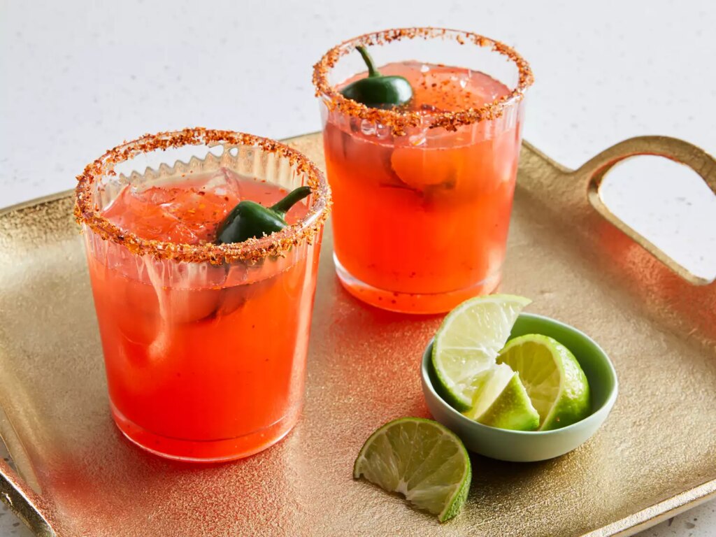 Close up on two glasses of vampiros mexicanos garnished with jalapenos and limes