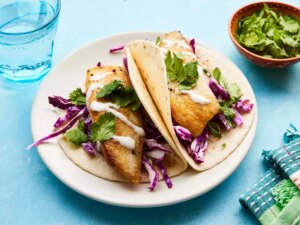 Looking at a plate of two fish tacos, garnished with cilantro