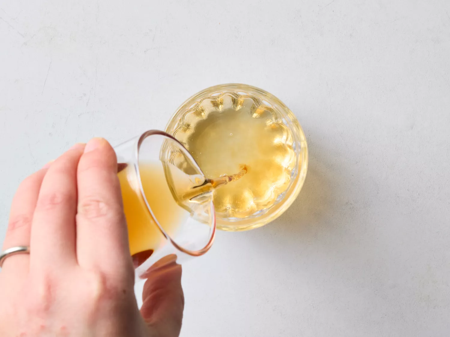 Hand pouring orange liquid into a glass