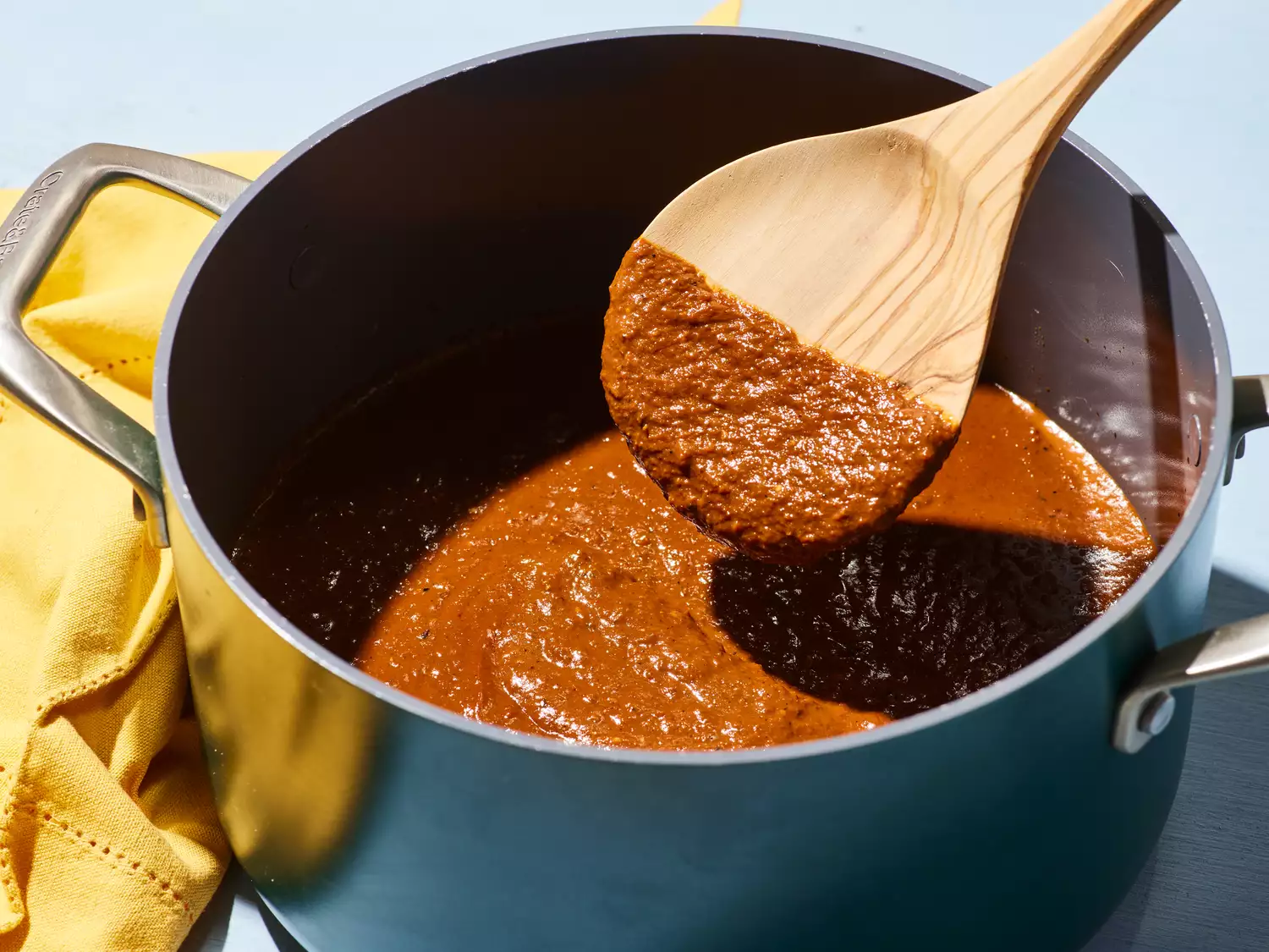 A coated spoon coming out of a pot of mole sauce