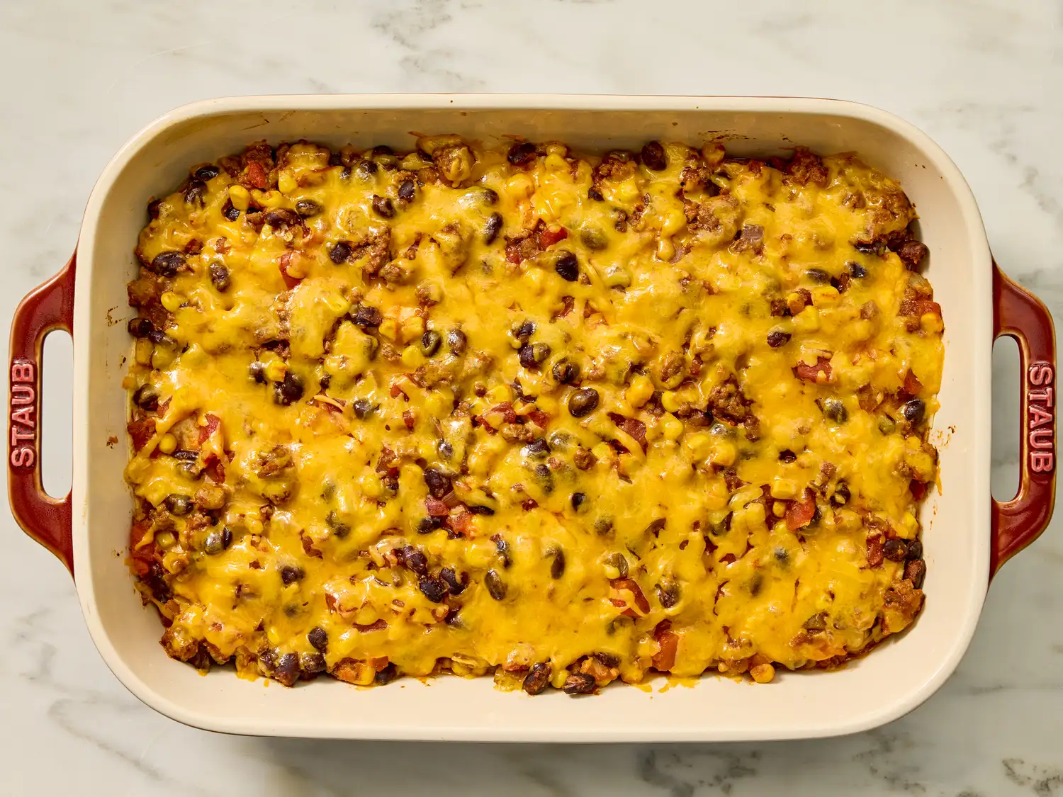 Baked casserole with melted cheese and visible beans in a rectangular dish