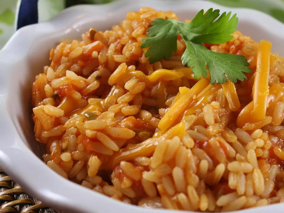 Close up view of arroz rojo (mexican red rice) garnished with fresh herbs in a bowl