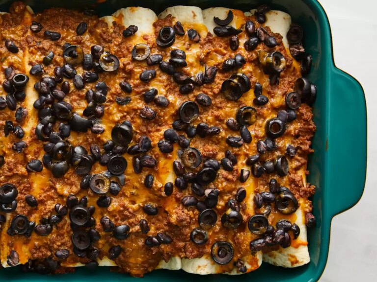 Close up view of baked beef enchiladas in a turquoise 9x13 casserole