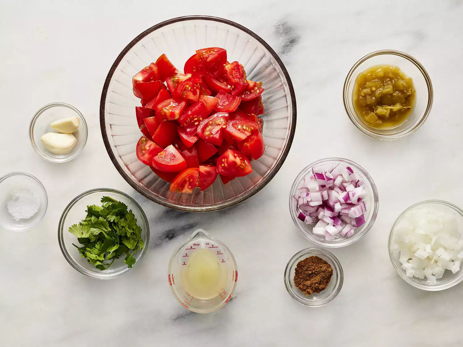Overhead of salsa ingredients in various sized bowls. 