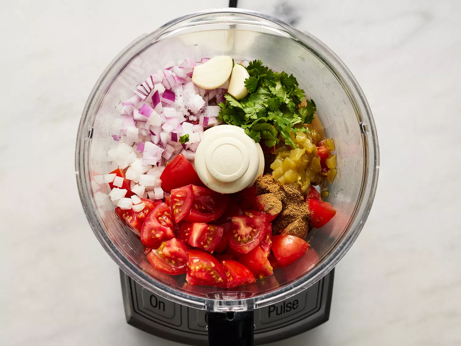 Overhead of salsa ingredients in a food processor. 