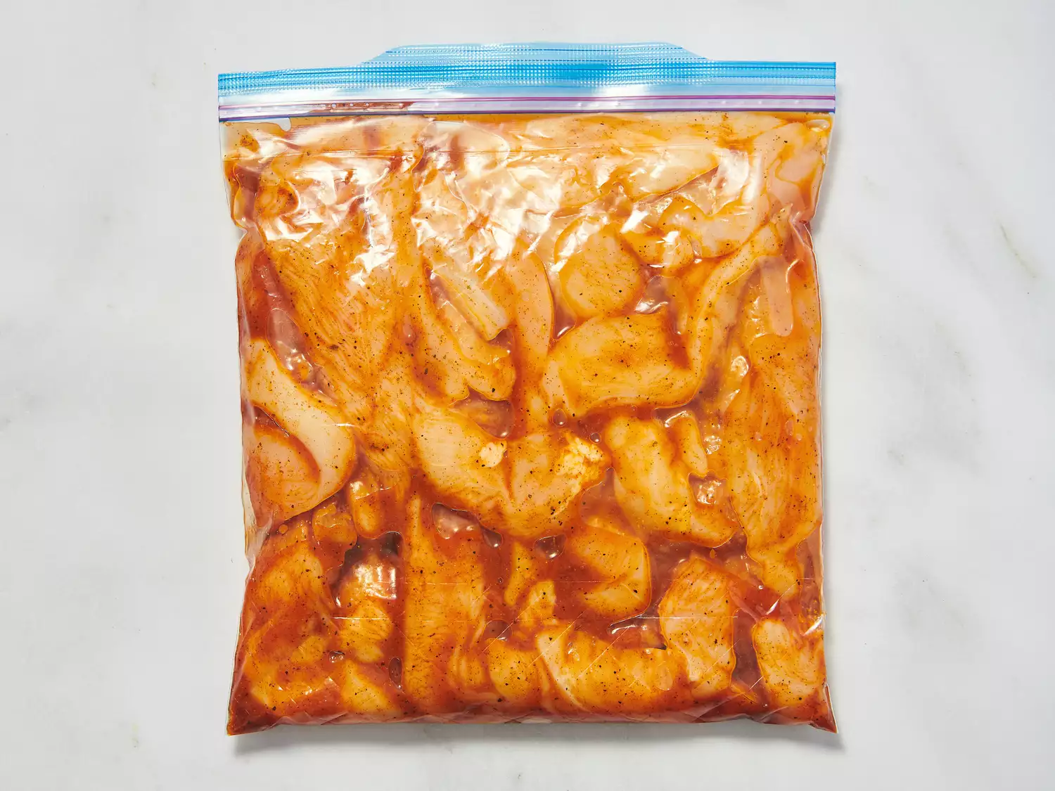 Chicken marinating in a sealed plastic bag with a fajita seasoning mix