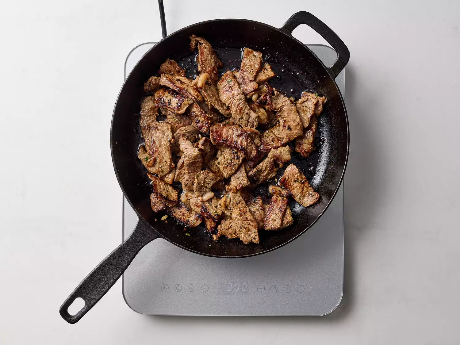 Cooked beef fajita strips sizzling in a cast-iron skillet