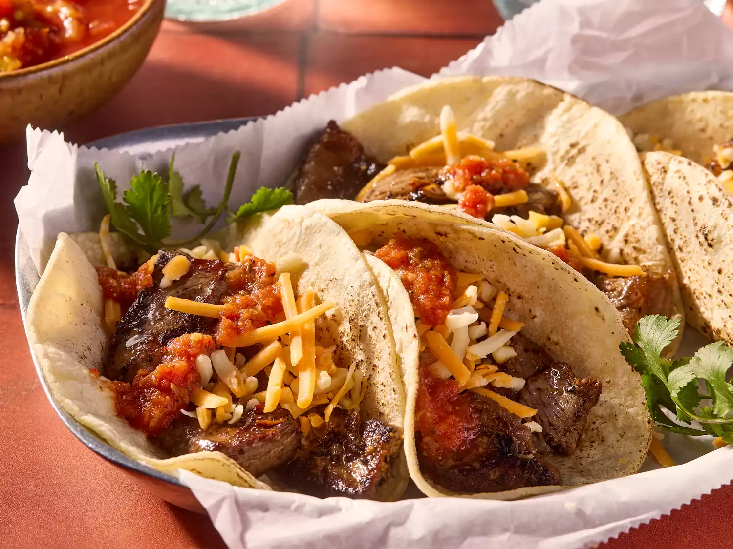 Beef fajitas with tortillas, salsa, cheese and fresh cilantro on a platter