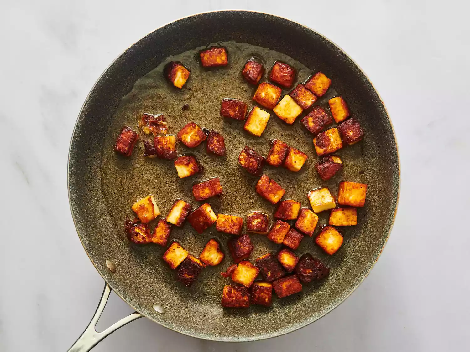 Cubed paneer being cooked in a skillet