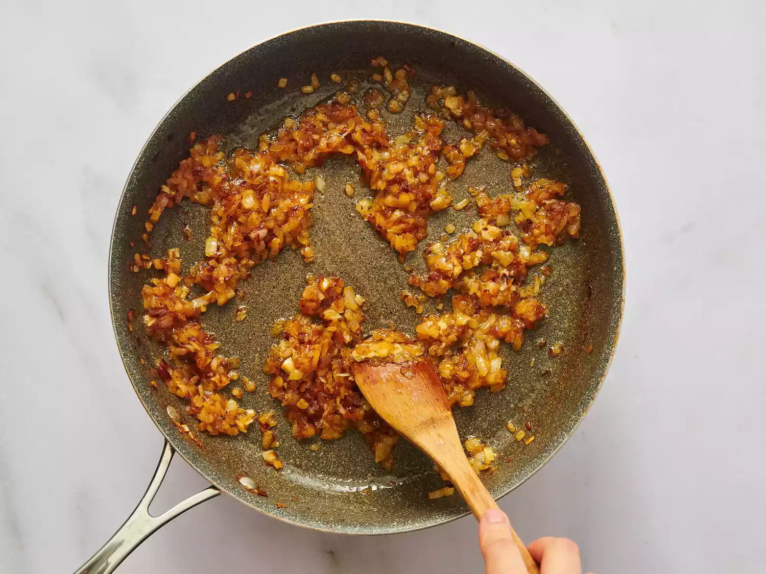 Cooking a spiced onion mixture in a pan with a wooden spoon