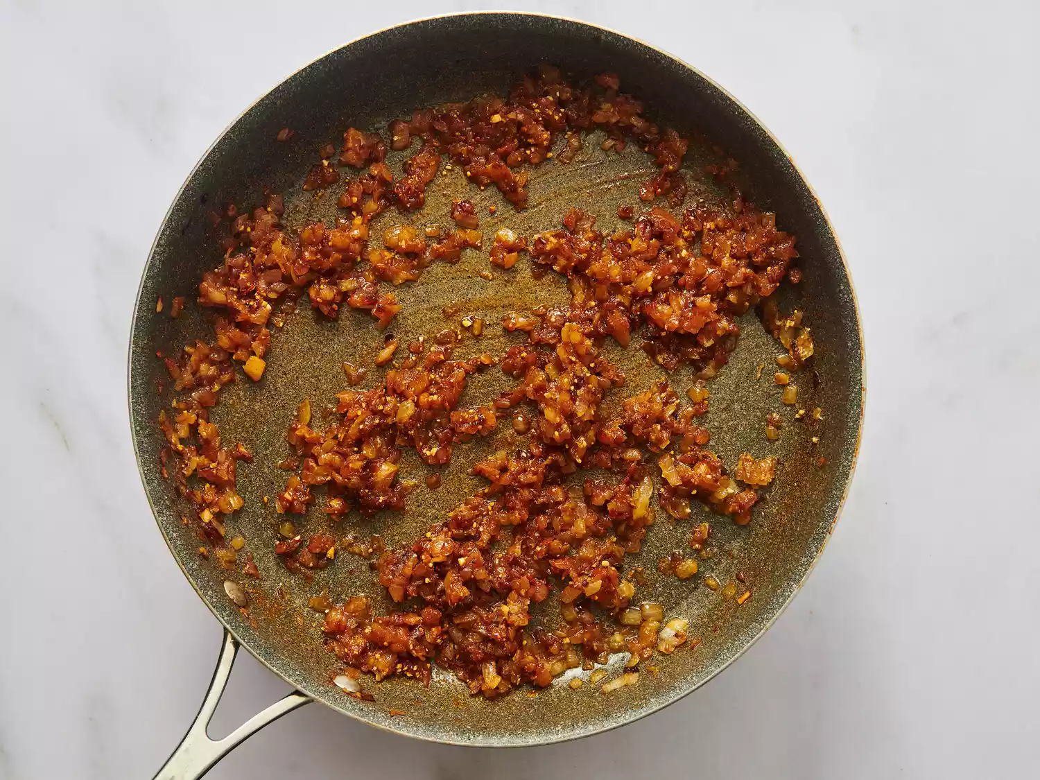 Cooking onion and tomato mixture in a pan to prepare paneer butter masala dish