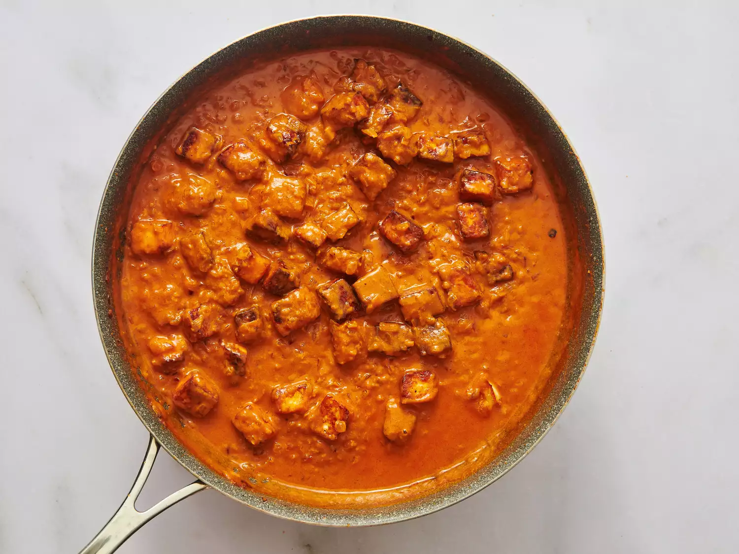 A pan with paneer butter masala being cooked