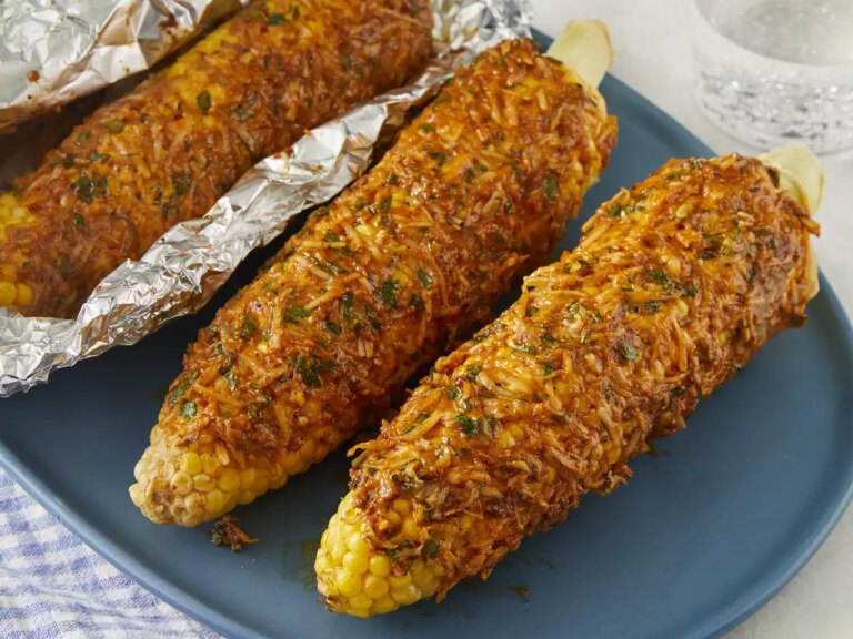 High angle looking at a blue plate of three oven roasted parmesan corn on the cob