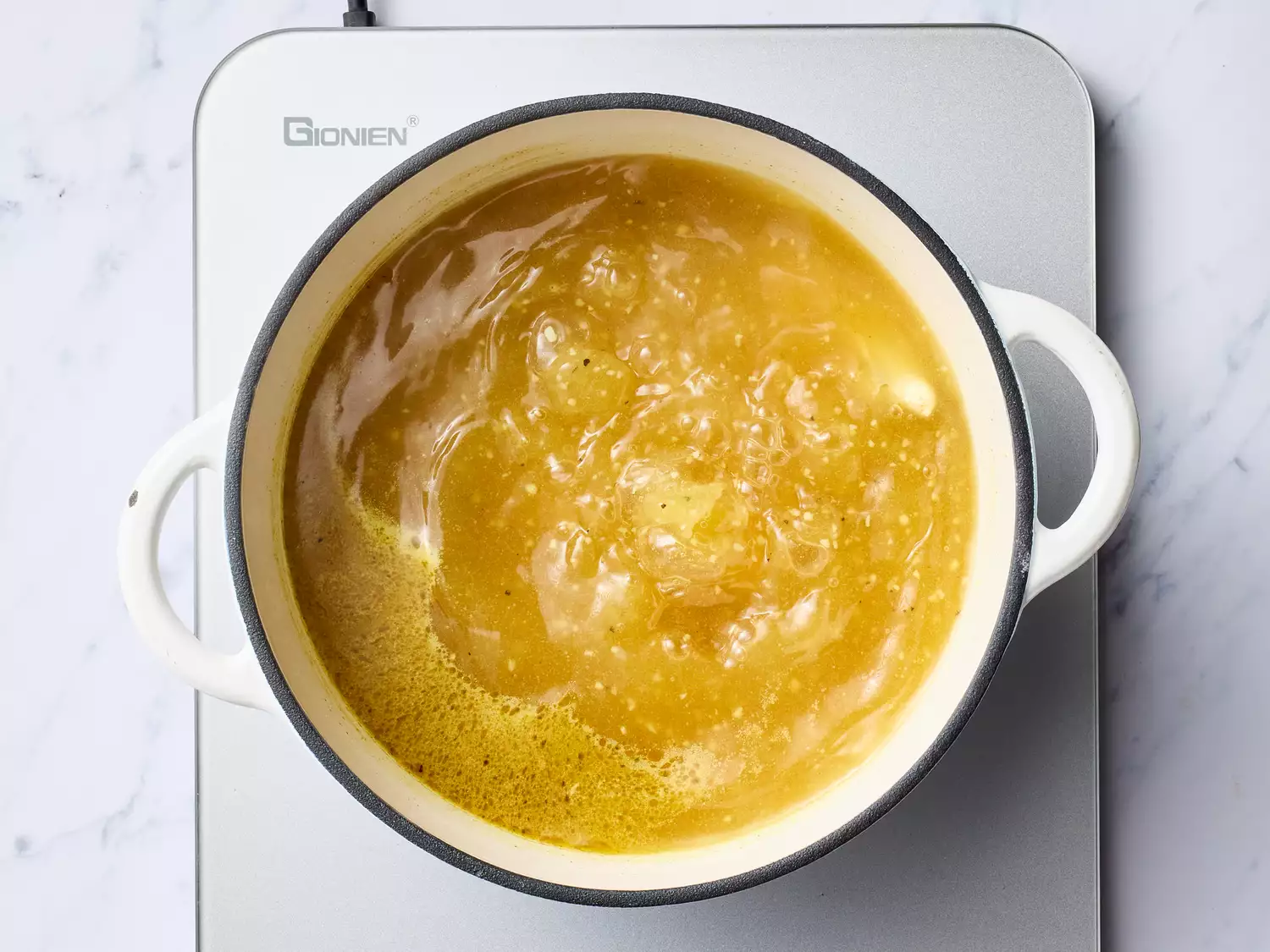 broth and seasonings added to a large pot, coming to a boil