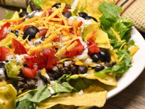 Close up view of black bean taco salad with tomatoes, and black olives on a plate