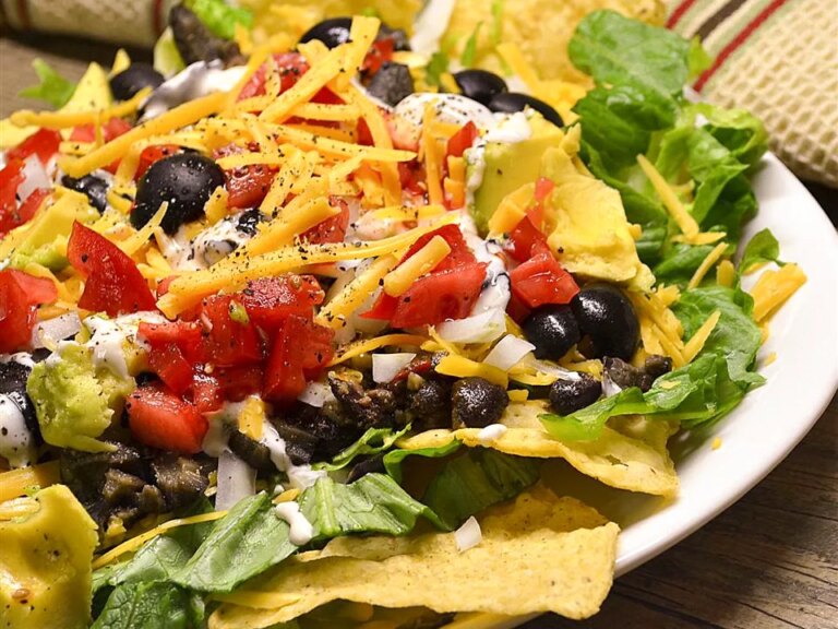 Close up view of black bean taco salad with tomatoes, and black olives on a plate