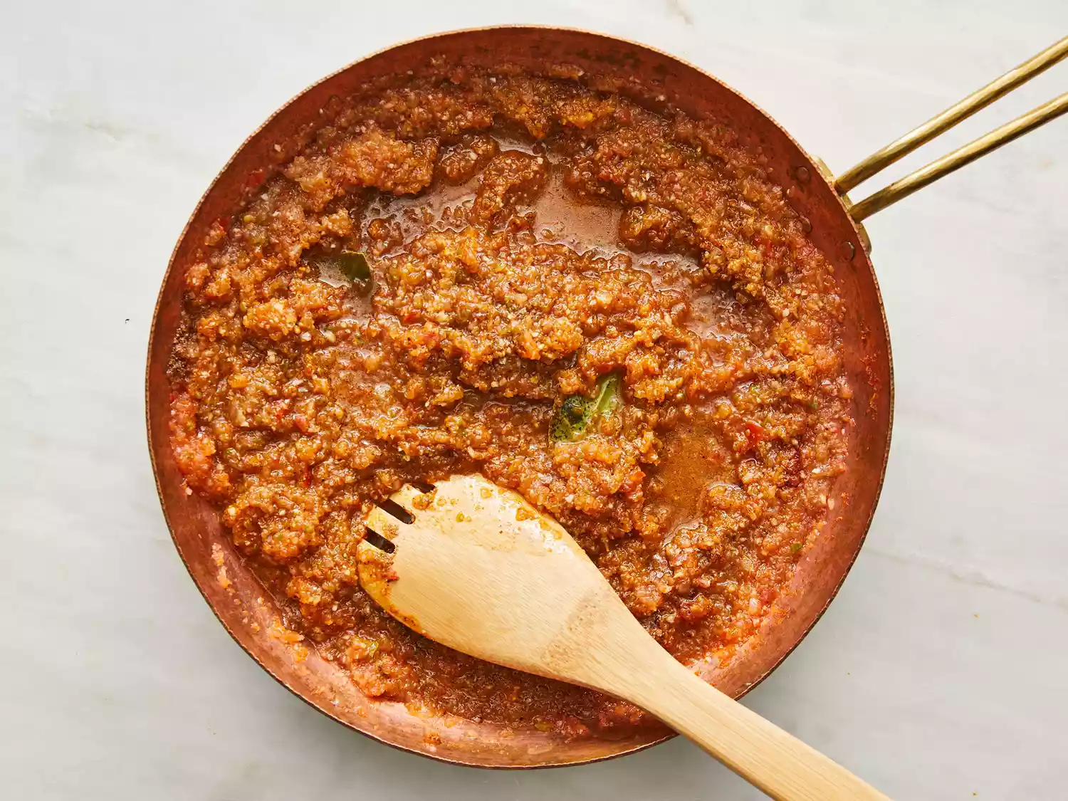 chana masala gravy in skillet with wooden spoon