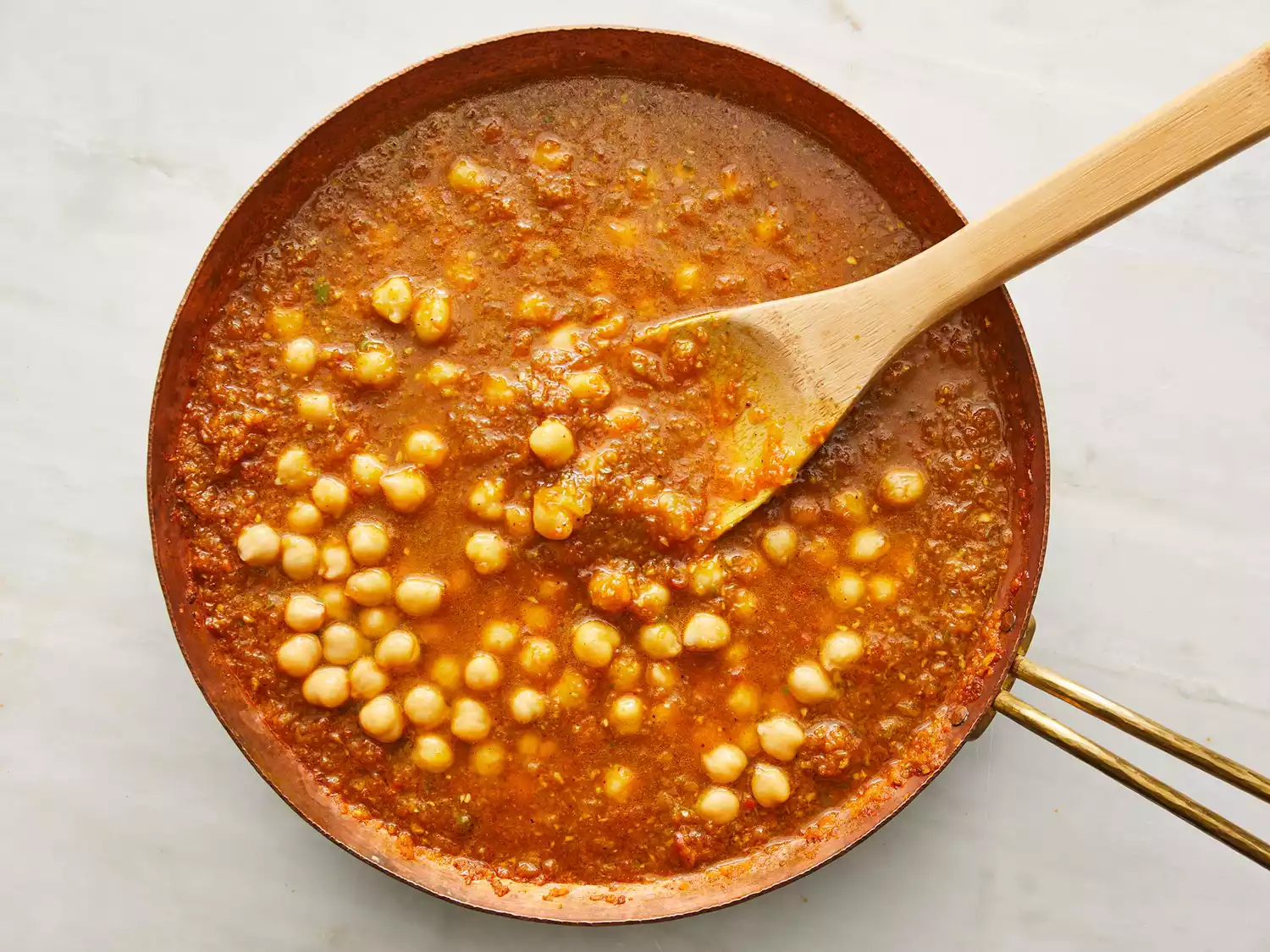 chana masala in skillet with wooden spoon