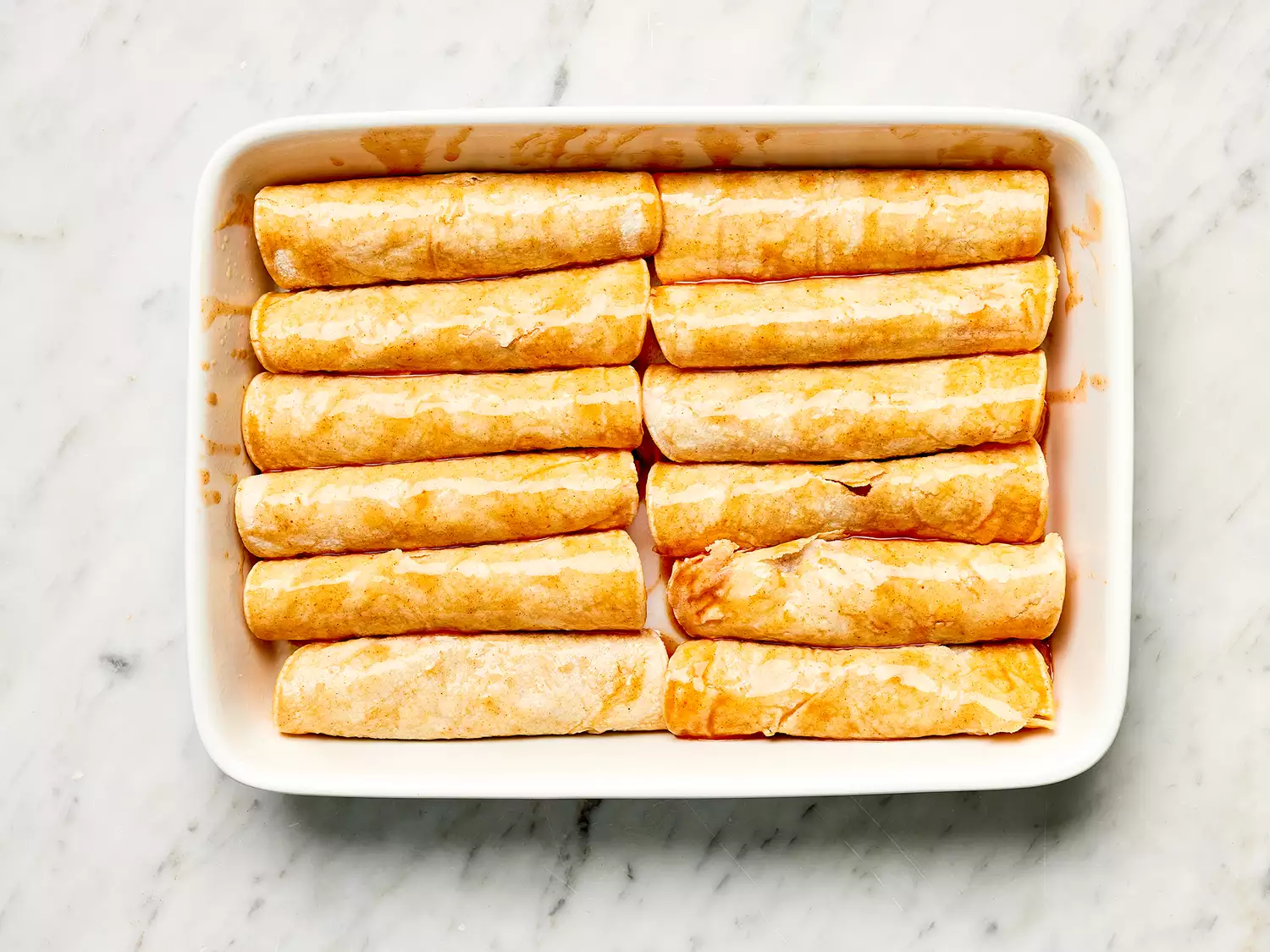 Refried Bean and Cheese Enchiladas in a white casserole dish 
