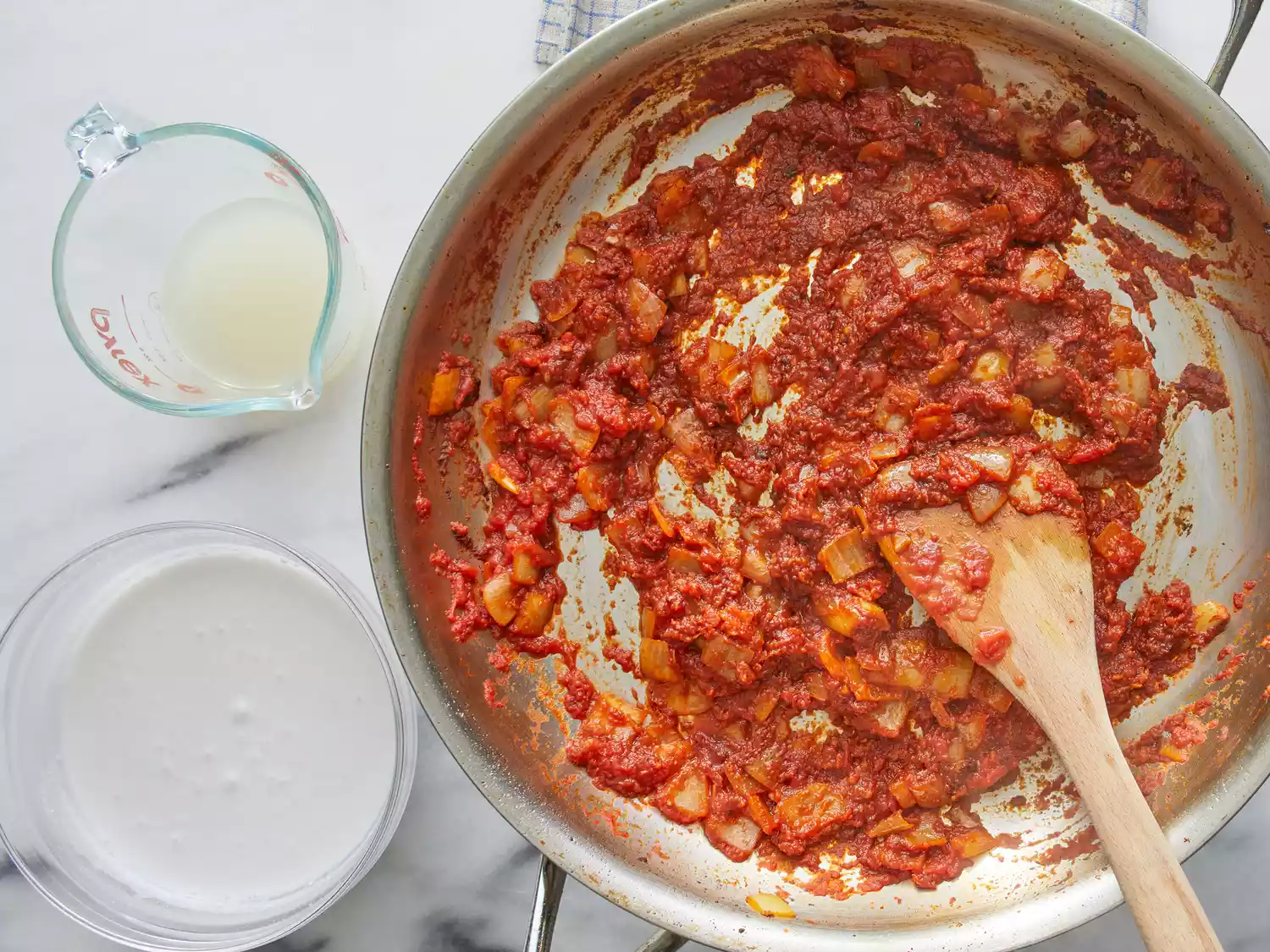 an overhead shot of crushed tomatoes add to a skillet with onions