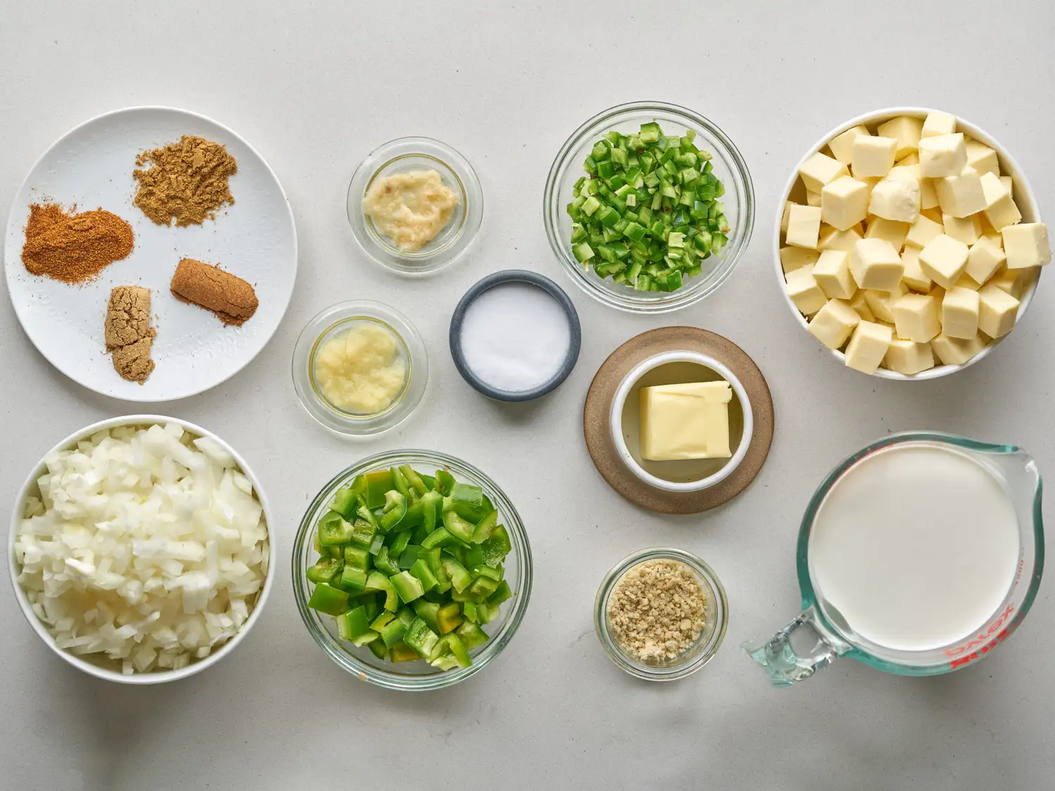 Key ingredients for paneer tikka masala in bowls and on a plate, including spices, diced paneer, vegetables, and milk
