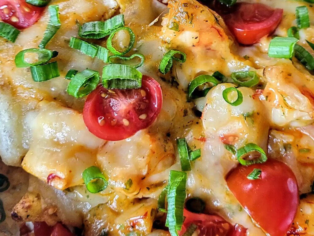Close up of shrimp nachos with cherry tomatoes and scallions