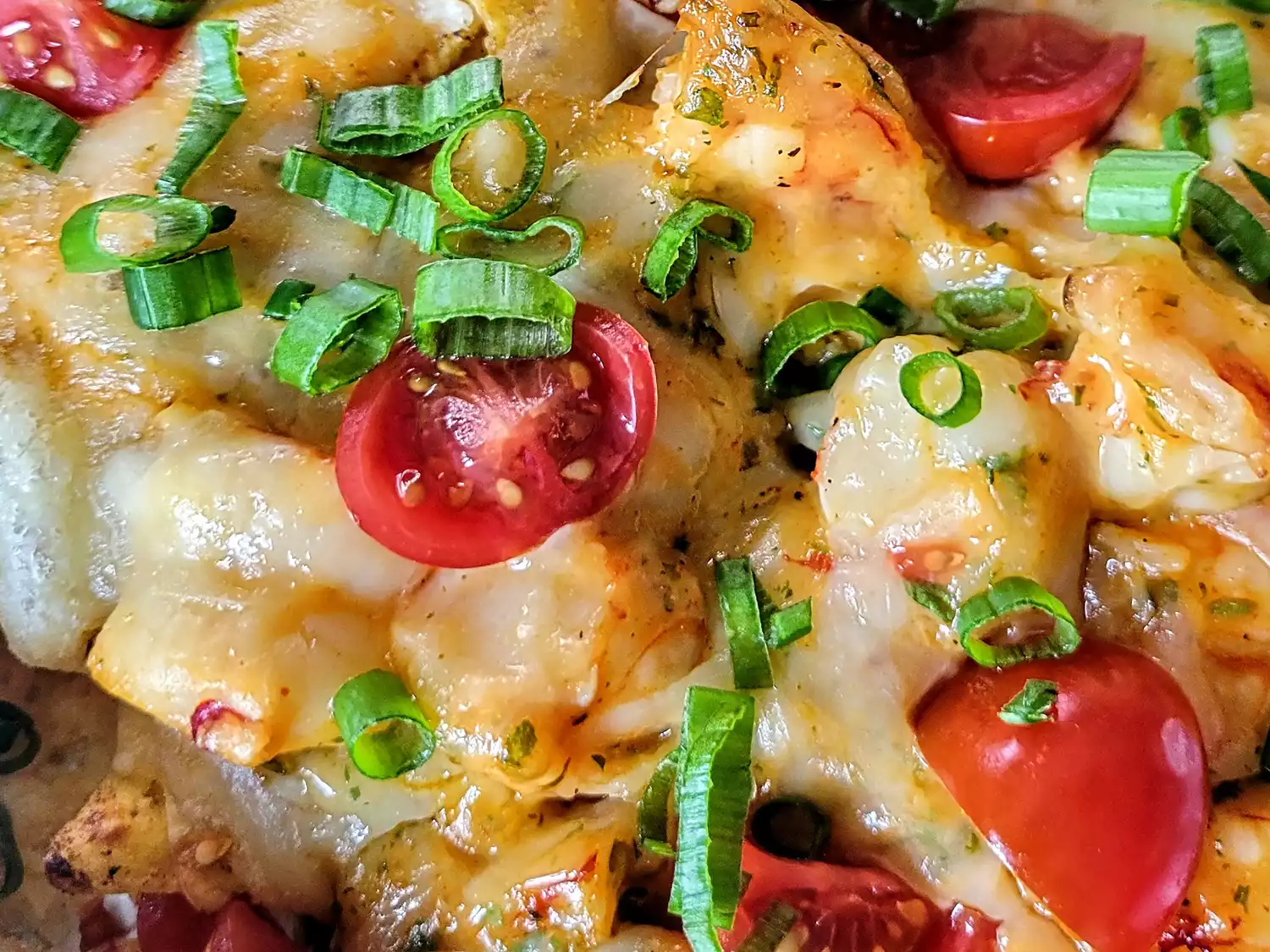 Close up of shrimp nachos with cherry tomatoes and scallions