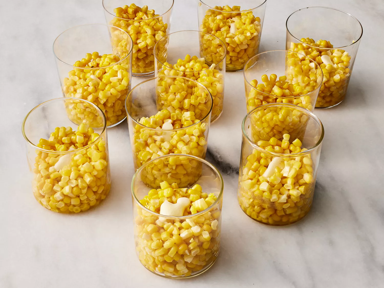 3/4 cup of corn kernels added to 10 small glass cups, topped with butter and salt