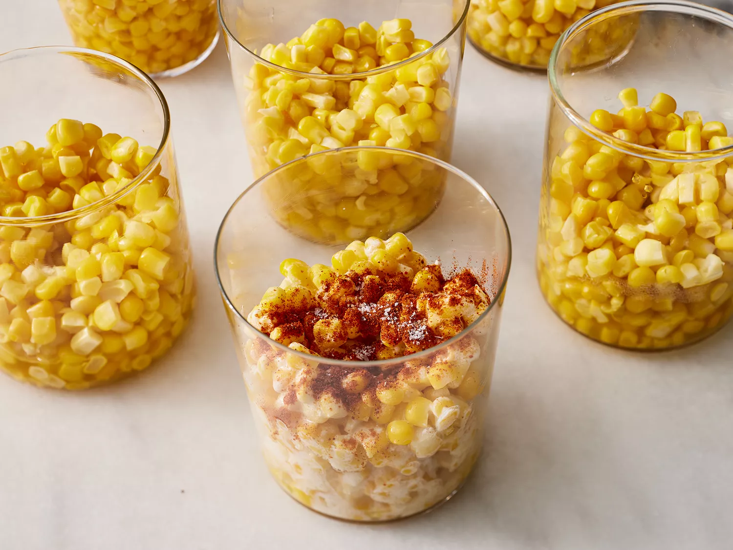 a close up on a cup of corn topped with butter, salt, and chili powder.