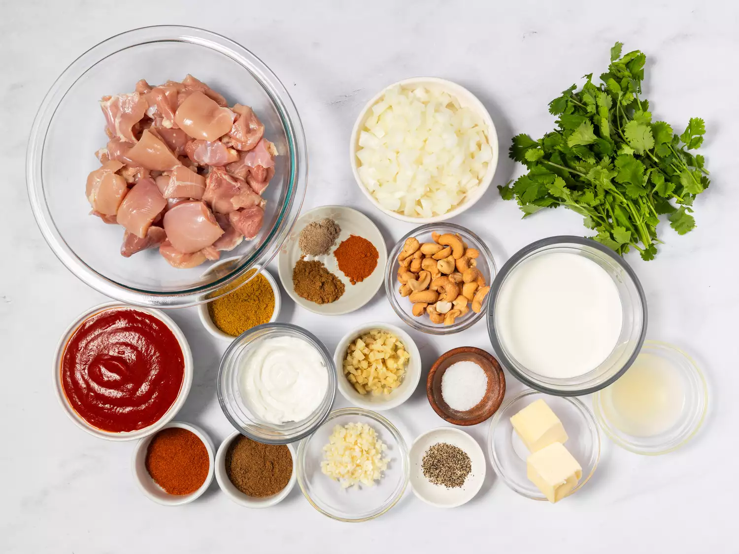Ingredients for Indian butter chicken arranged in bowls on a countertop