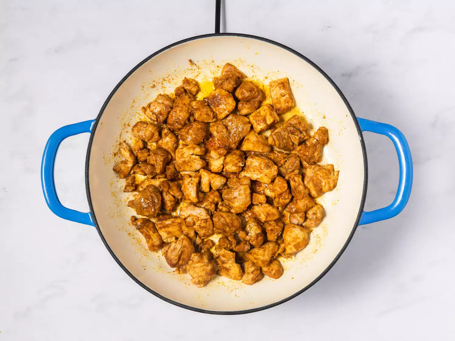 Cooked chicken pieces in a round pan with handles