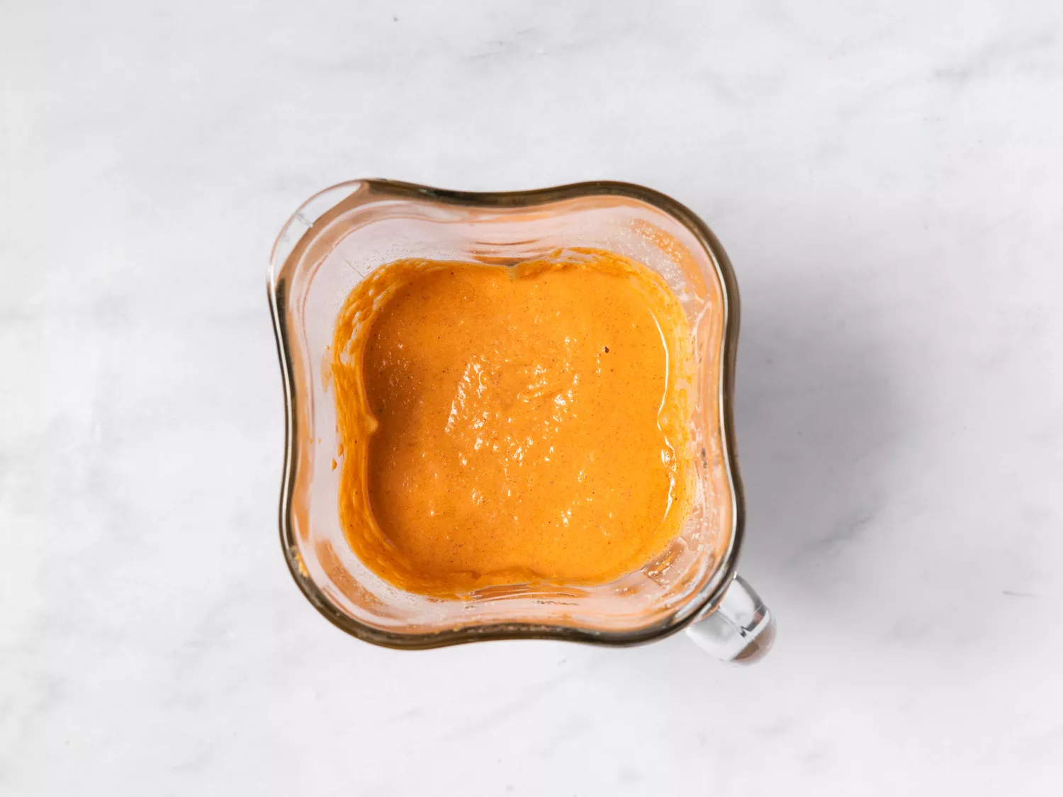 Blender jar containing orange-colored butter chicken sauce preparation
