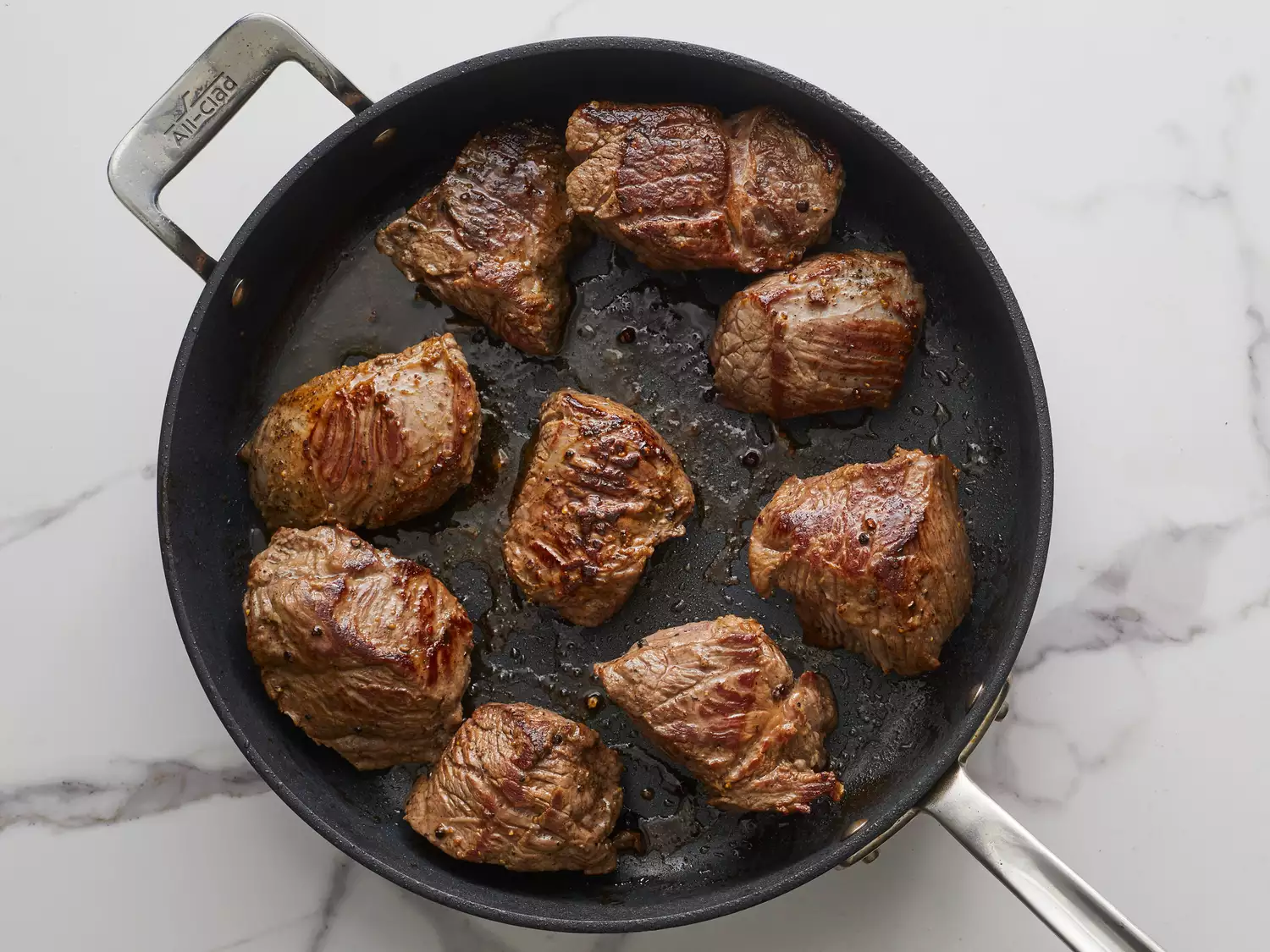 an overhead shot of beef chuncks searing in a skillet