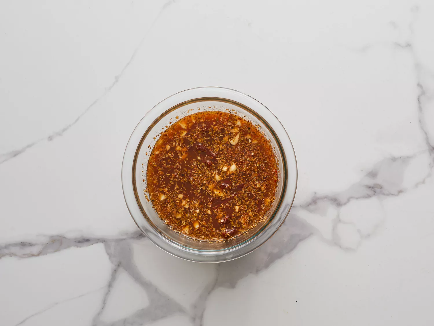 an overhead shot of broth, vinegar, lime juice, chipotle peppers, garlic, cumin, oregano, and cloves combined in a bowl